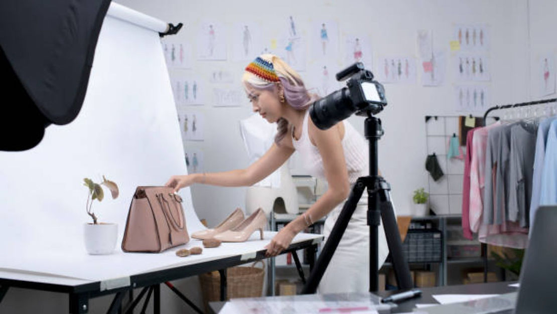 woman taking a picture of a bag, a small plant and a pair of heels
